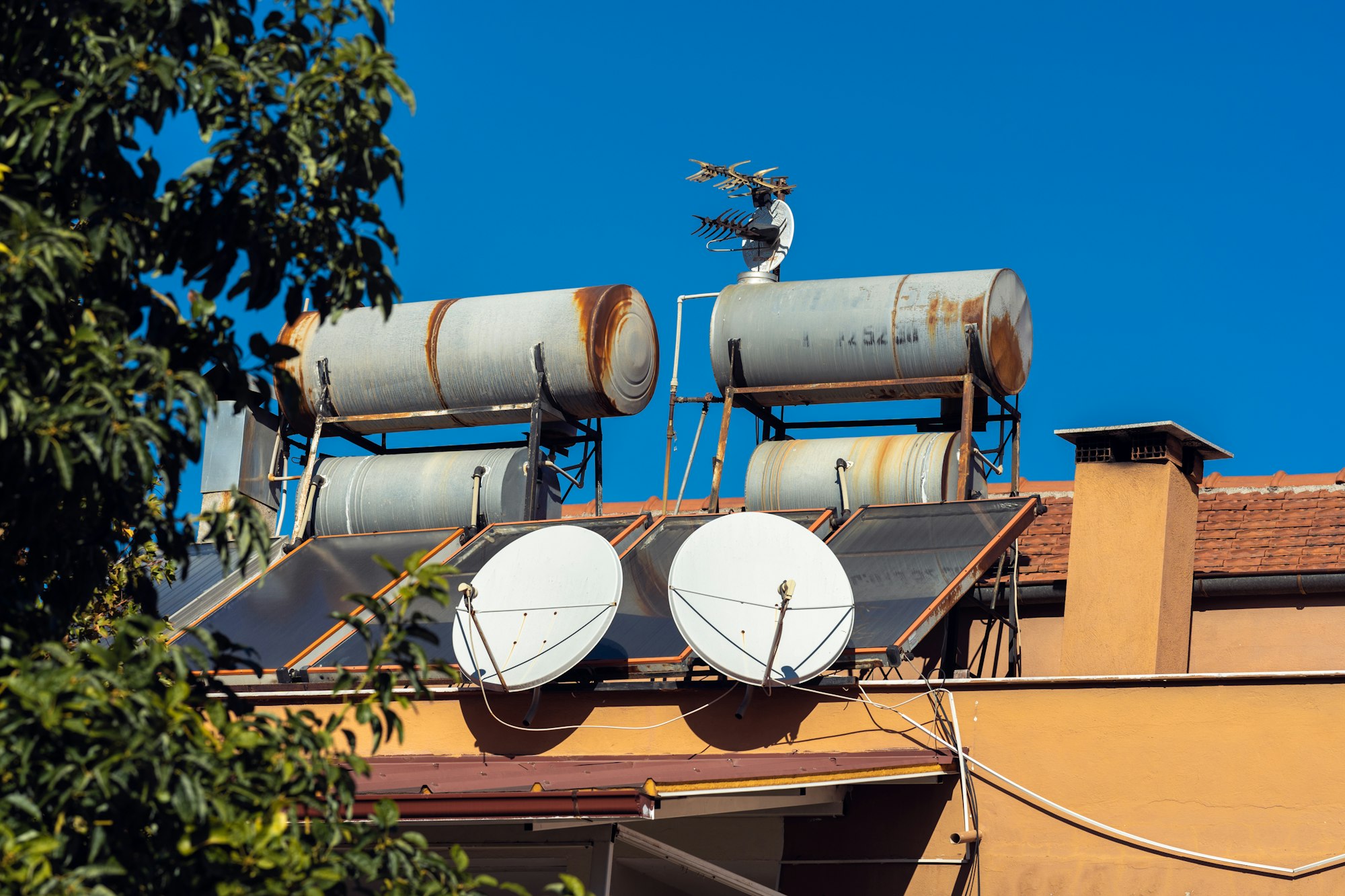Water tanks, solar panels and TV antennas on house roof.